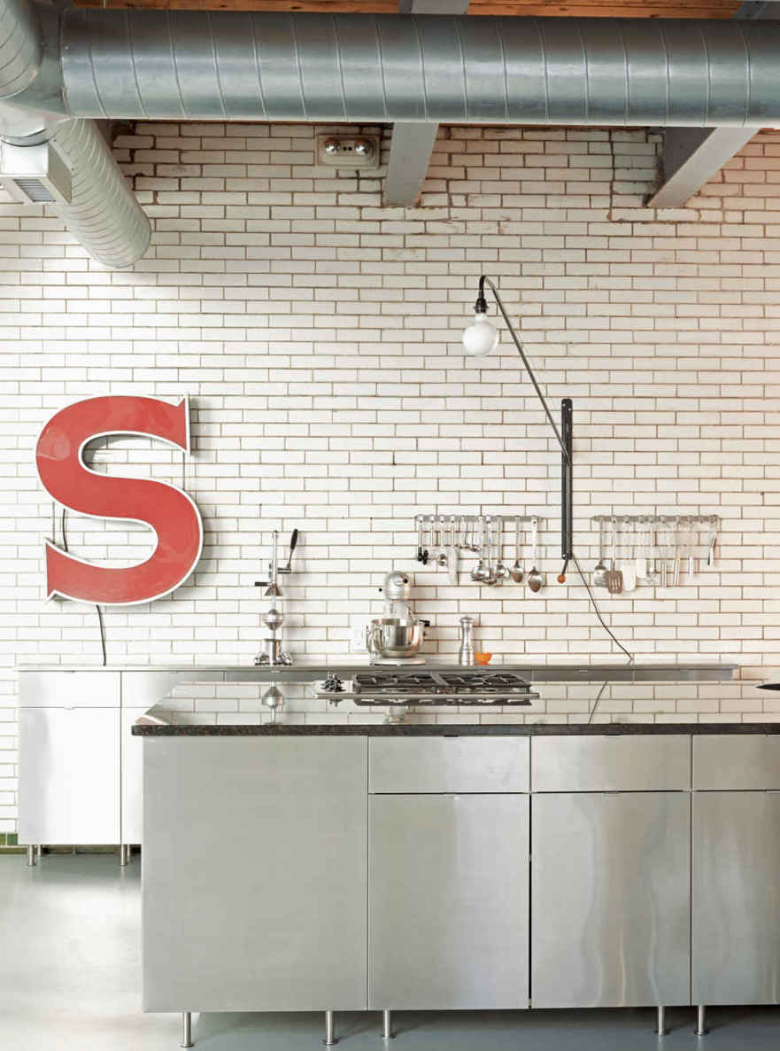 HIGH + LOW DONE RIGHT. Stainless steel cabinetry, arranged in an island configuration, looks high-end but isn’t, leaving room in the budget for a standout light fixture. Prouv&eacute;’s Potence swivel lamp is a classic.